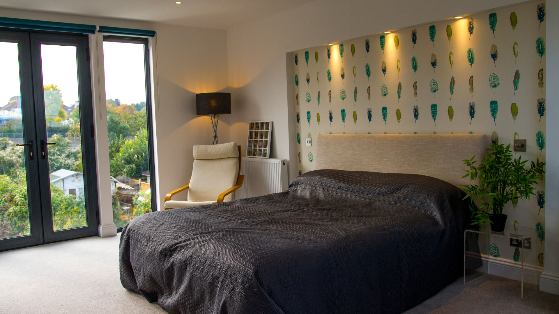 A striking set of French doors, flanked by floor-to-ceiling windows, floods a loft bedroom suite with natural light.