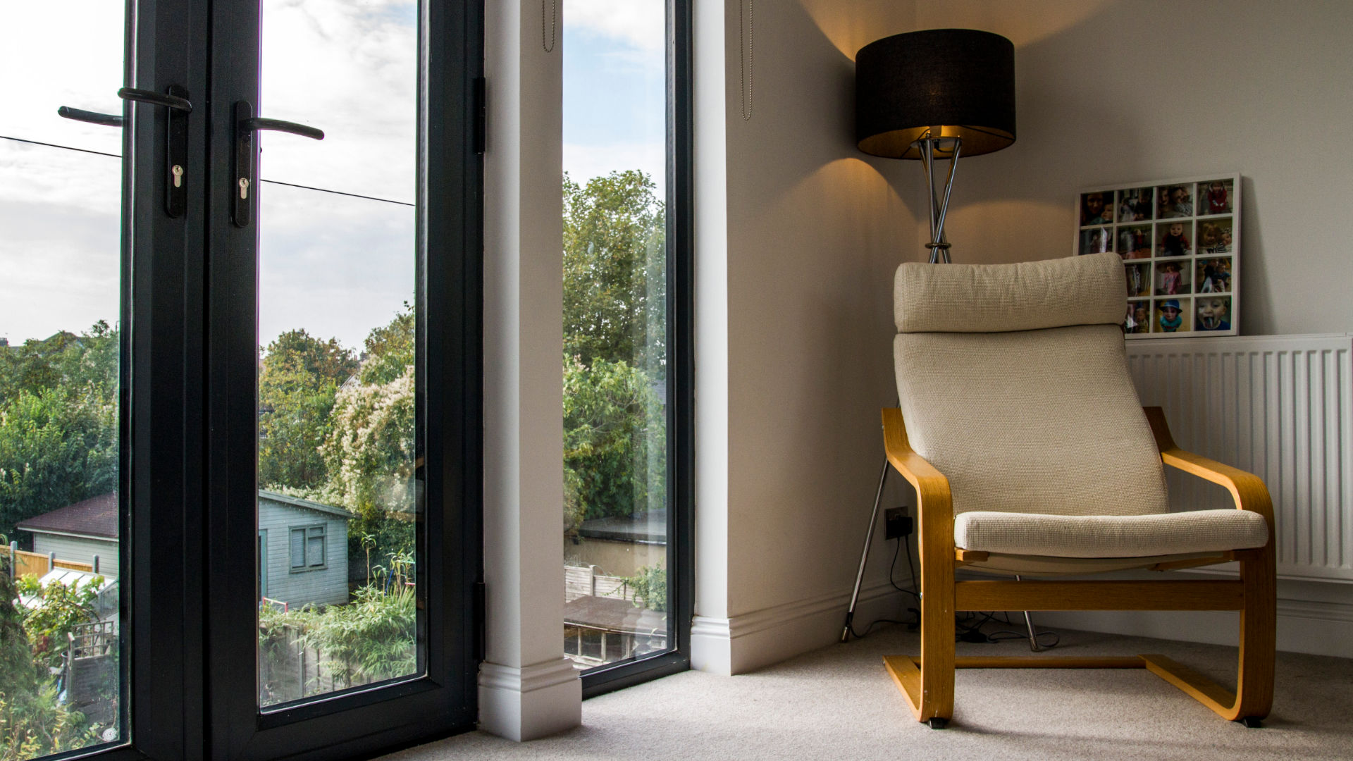 Modern, curved wooden chair takes pride of place in a bright, newly converted loft bedroom in London.