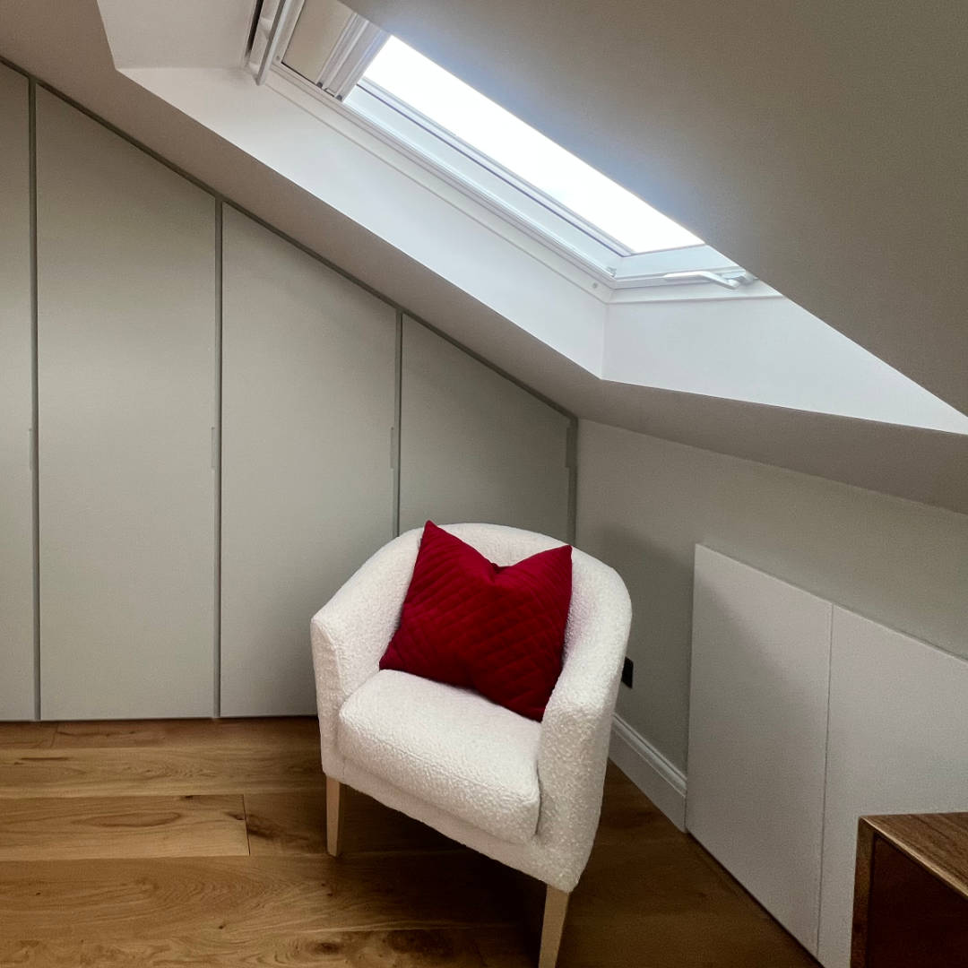 herne-hill-road-detail-velux A white bucket chair sits in the light of a large Velux loft window. Behind, sleek built-in storage makes the most of the wall-space in this South London loft.