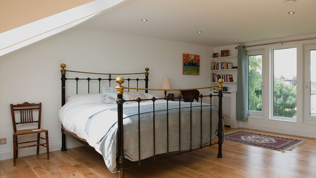 Close-up of a sleek, brushed-steel Velux window handle in a London loft bedroom.
